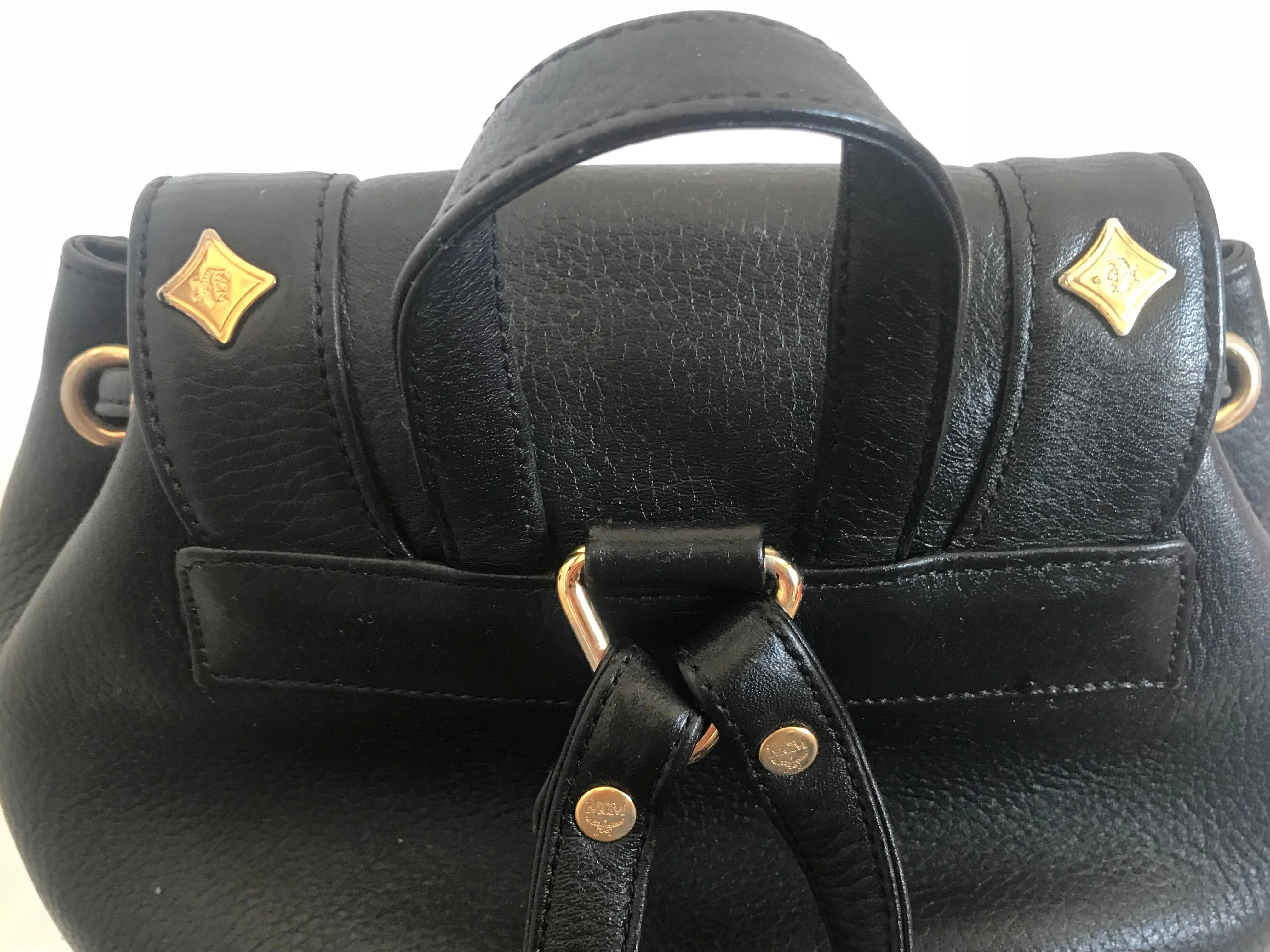 Vintage MCM black backpack with golden studded logo motifs and drawstrings. Designed by Michael Cromer. Unisex bag for daily use.